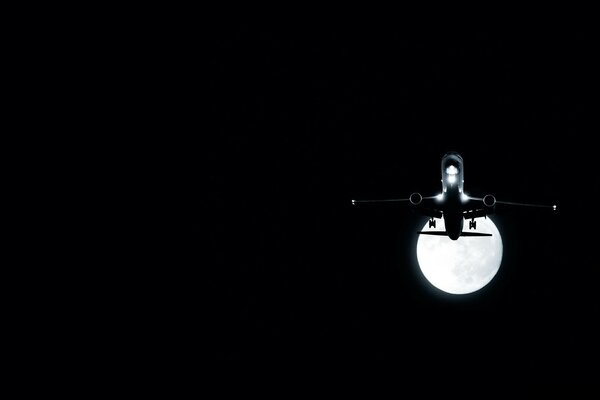 Avión en la oscuridad contra la Luna