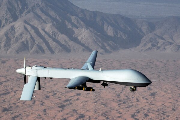 A drone plane flies over the desert hills