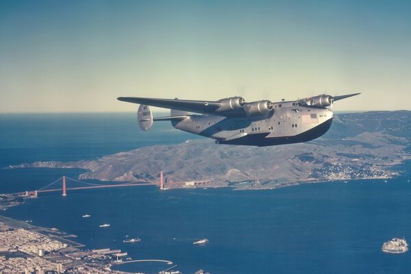 A blue plane flies over the water