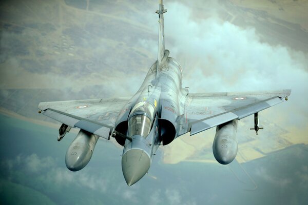The dassault mirage 2000 fighter is flying high above the ground