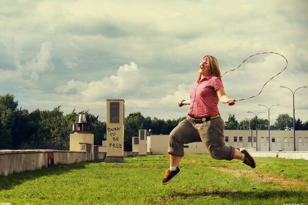 A girl jumps on a rope in the grass