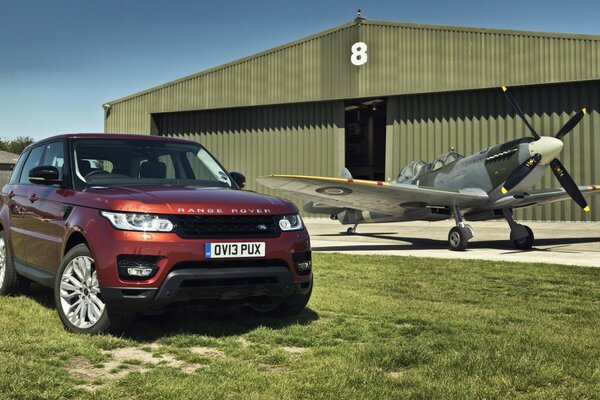 Ein roter Range Rover steht am Hangar und am Flugzeug