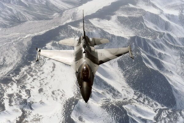 A military plane flies over snowy mountains