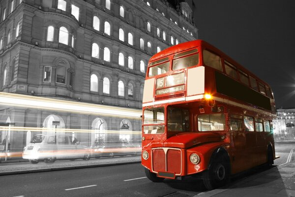 Red bus on the road of a black and white city in England