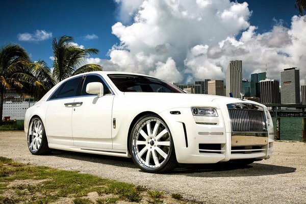 Weißer Rolls Royce auf Palmen und Stadt Hintergrund