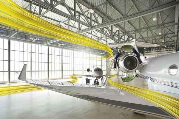 Un avión amarillo envuelto en cintas se encuentra en un hangar