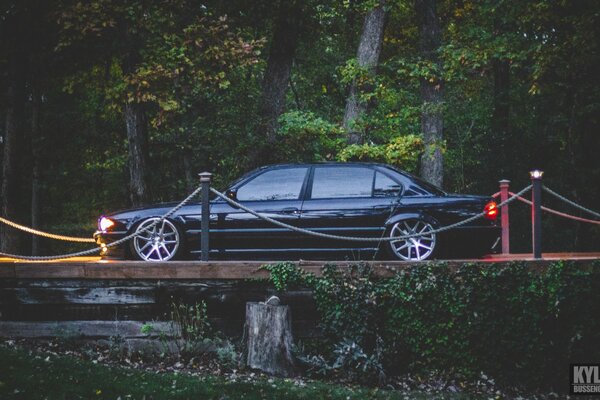 BMW E38 740iL nero sul ponte con fari accesi vista laterale