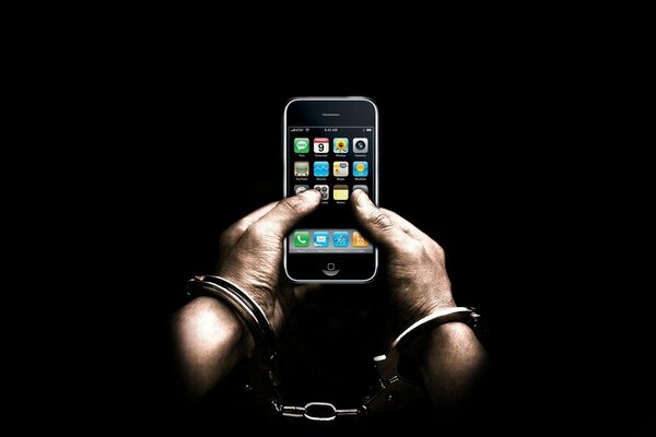 Мужские руки в наручниках держат телефон