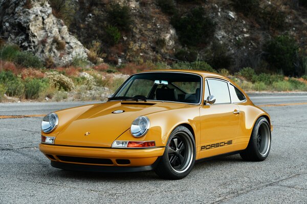 A mustard-colored Porsche is standing on the road