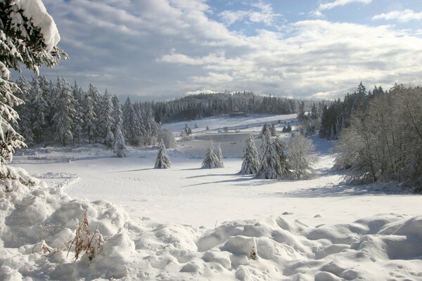 Winter und Schneeverwehungen im Hintergrund von Bergen und Wäldern