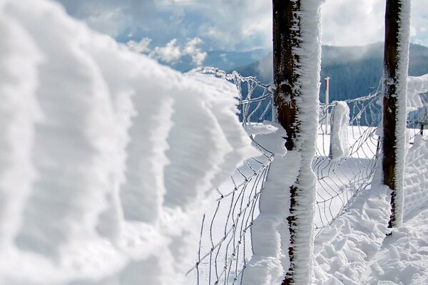 Schneezaun auf dem Hintergrund der Winterberge