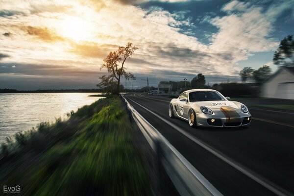 Porshe en la puesta del sol, corriendo por la pista a lo largo del mar