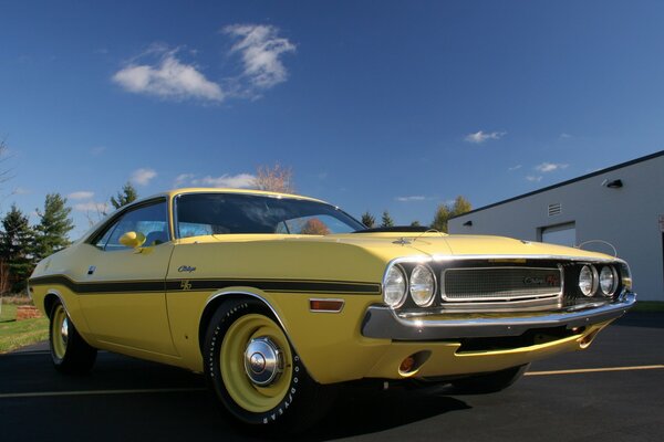 A yellow retro car is parked on the road next to the garage