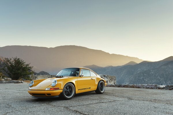 Porsche amarillo en el fondo de hermosas montañas