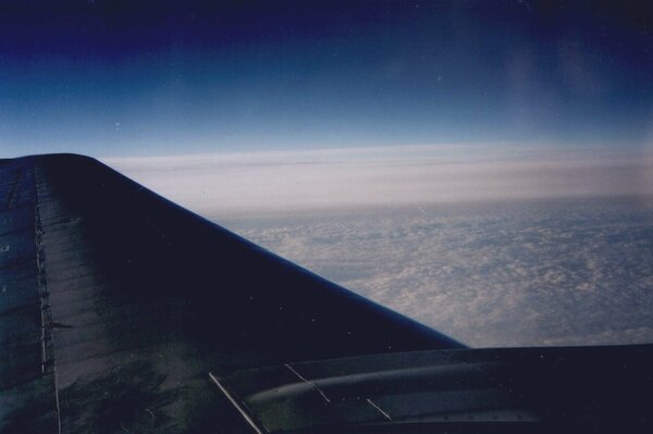 Blick vom Bullaugen auf den Flugzeugflügel und die Wolken