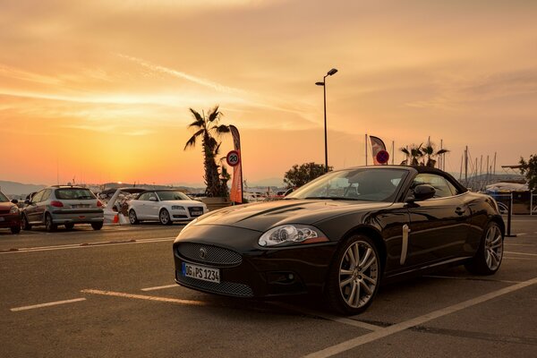 Coche deportivo en el estacionamiento en medio de la puesta de sol