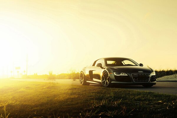 Black supercar in the rays of the rising sun