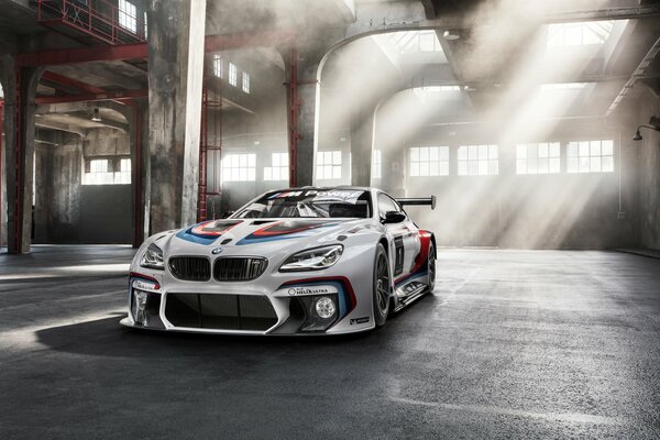 Voiture de sport de couleur blanche dans un hangar rempli de soleil