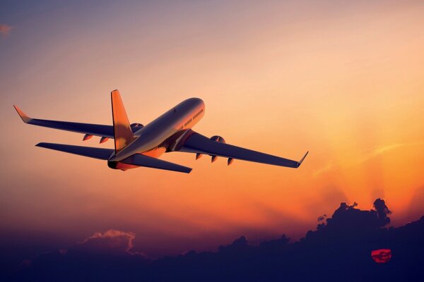 The plane with passengers is flying at sunset