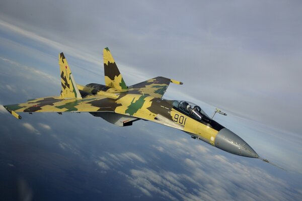 The SU-35 fighter flies over the blue ocean