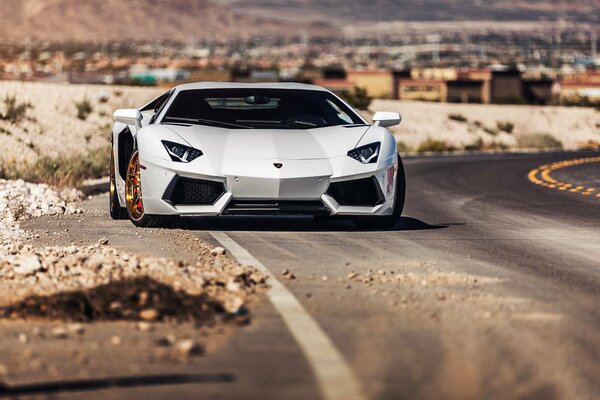 Une supercar blanche lamborghini roule sur une route dans le désert