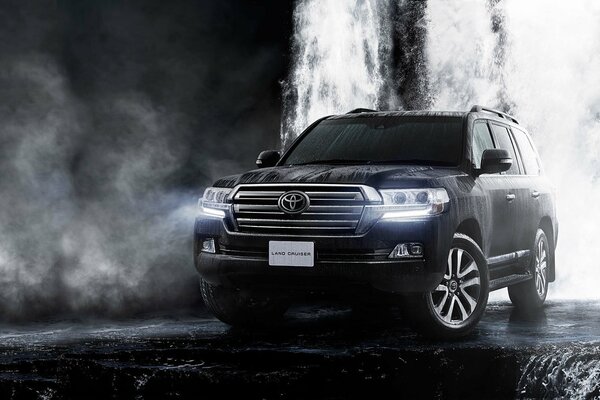 Schwarzer Toyota Land Cruiser am Wasserfall im Dunst