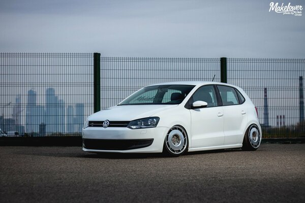 A low-tuned car is standing near the fence