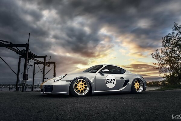 Elegante Porsche Caimán tuneado en el fondo de las nubes