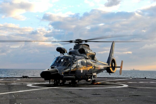 A helicopter on the deck of an aircraft carrier is preparing for takeoff