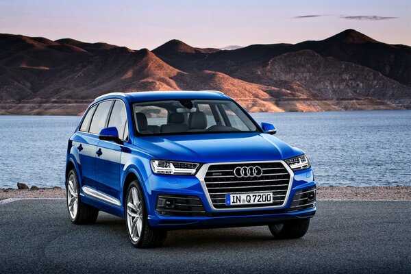 Bright blue audi q7 2015 on the background of a mountain pond