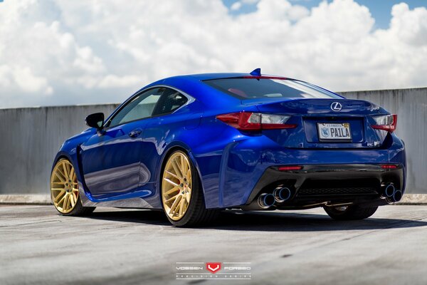 Leuchtend blauer Lexus mit goldenen Scheiben vor einem Hintergrund von Wolken