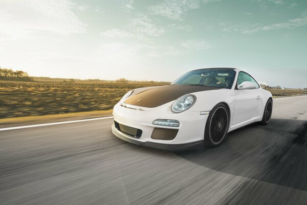 Porsche blanco con capucha negra en la pista