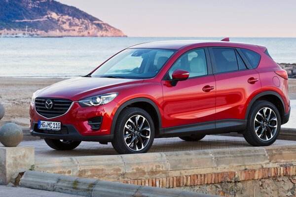 Автомобиль mazds cx-5 красного цвета на берегу залива