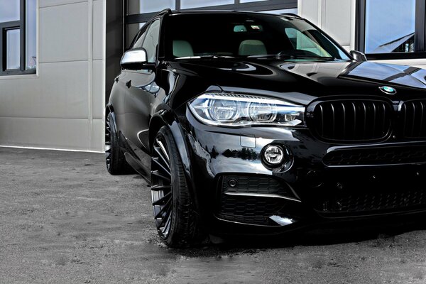 El BMW X5 negro tuneado se encuentra junto al edificio