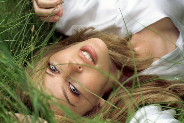 Chica de pelo claro sonríe sexualmente acostado en la hierba