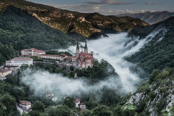 A huge castle rises above the trees in the mountains