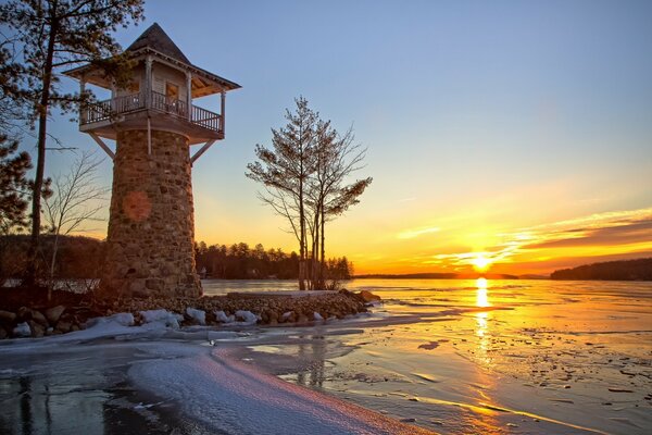 Paysage avec phare sur fond de coucher de soleil