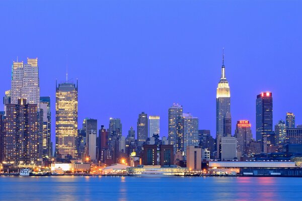Wolkenkratzer von New York vor dem Hintergrund des blauen Himmels. Die Nacht. Die USA