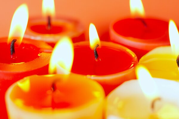 Colored, lit candles on an orange background