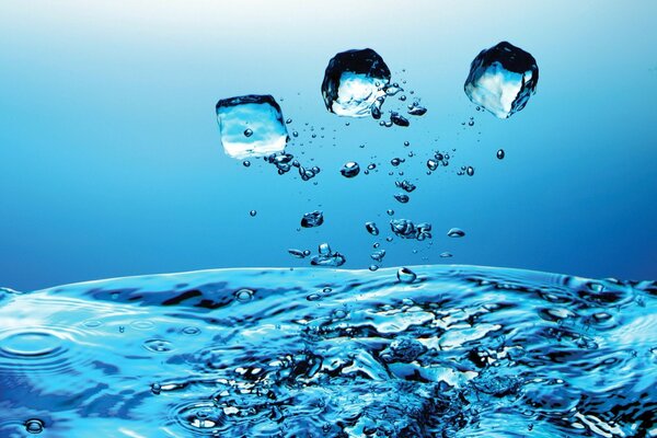 Trozos de hielo y gotas sobre un fondo azul