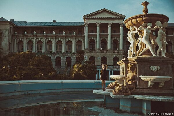 A girl stands on a fantan and poses against the background of the palace