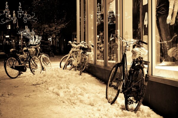 Snow-covered bicycles on the night street