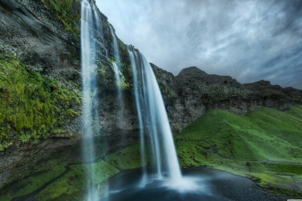 Islands Wasserfall und grüne Hügel