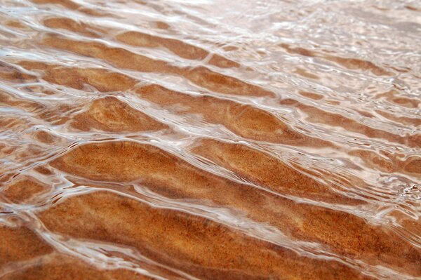 Sand durch die Wellen der Meereswellen