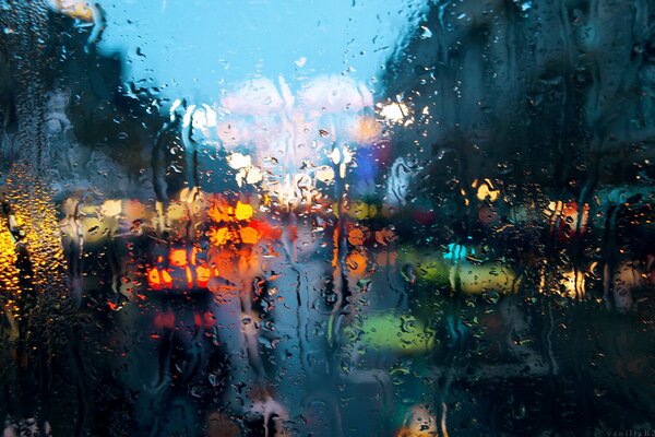 Regentropfen auf Glas vor dem Hintergrund der Lichter der Stadt
