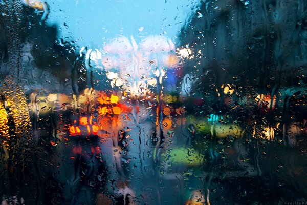 Gotas de lluvia sobre el cristal en el fondo de las luces de la ciudad