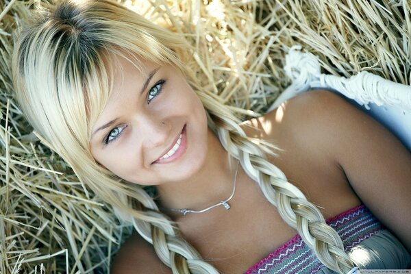 Young green-eyed blonde on dry grass