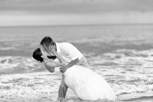 Bianco e nero sposo baciare la sposa in riva al mare