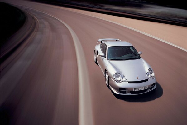 A gray car is driving on the road at high speed