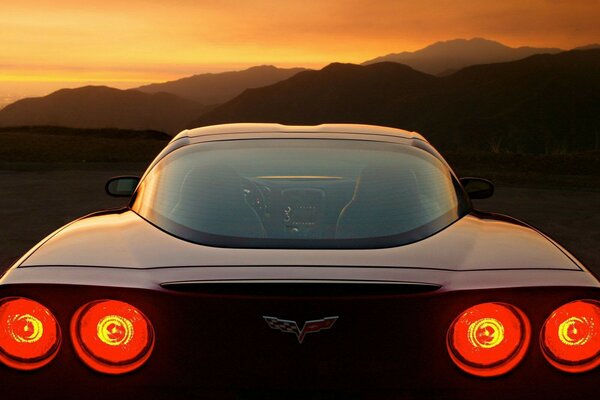 A car in the back with its headlights on against the sunset